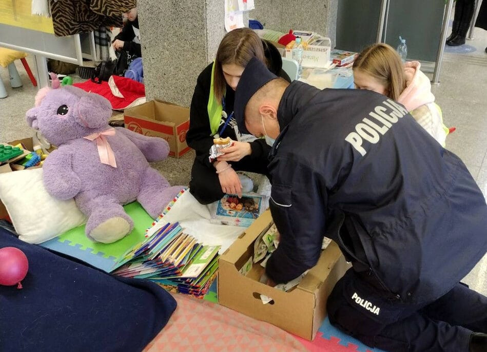 Policjant pomaga dzieciom w zbieraniu zabawek i książek, które następnie przekazuje na cele charytatywne.