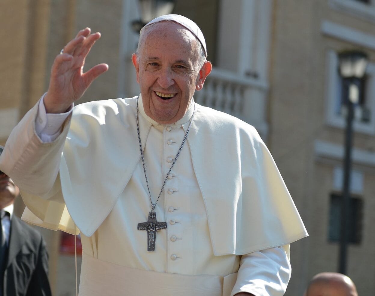 Papież Franciszek uśmiecha się i macha