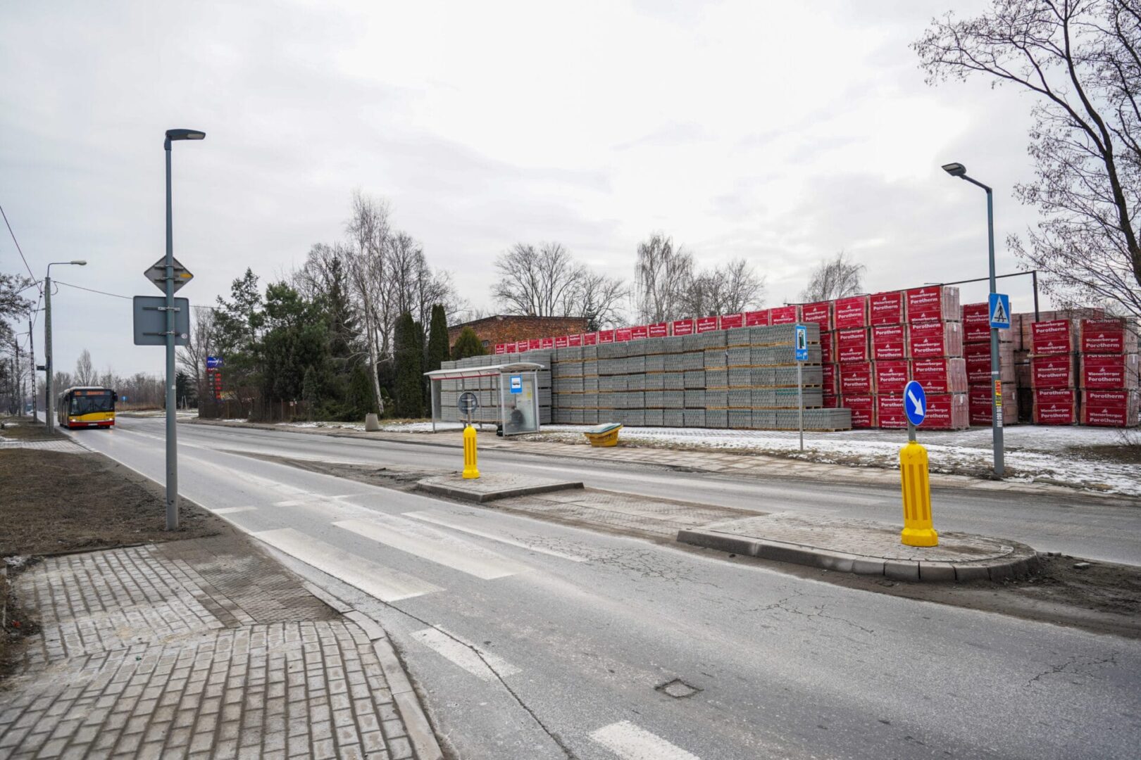 Przystanek autobusowy ze składowanymi materiałami budowlanymi i przejściem dla pieszych