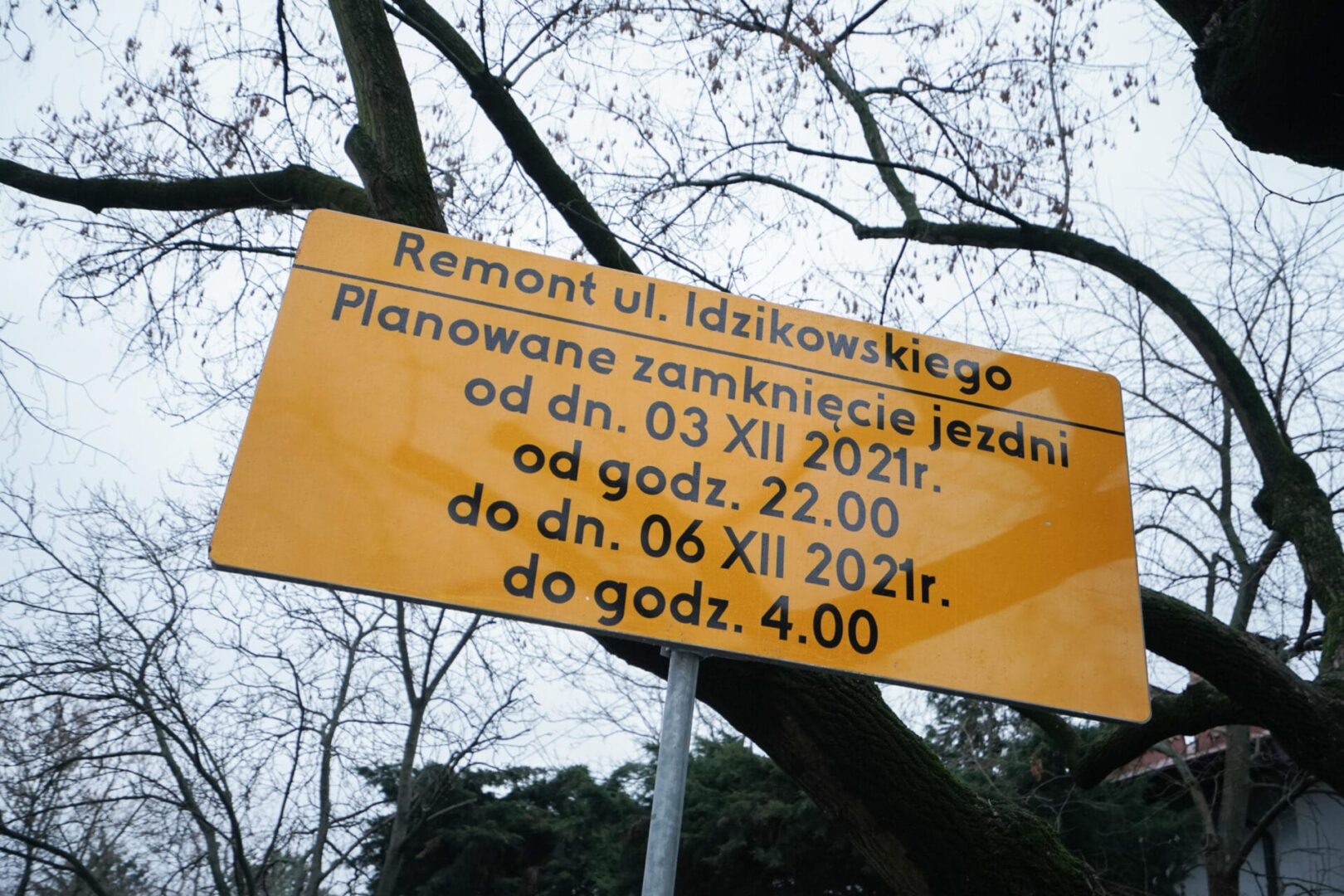 Żółty znak informujący o zamknięciu drogi: Ulica Idzikowskiego zamknięta od 3 do 6 grudnia 2021 r. w godzinach 22:00 - 4:00.
