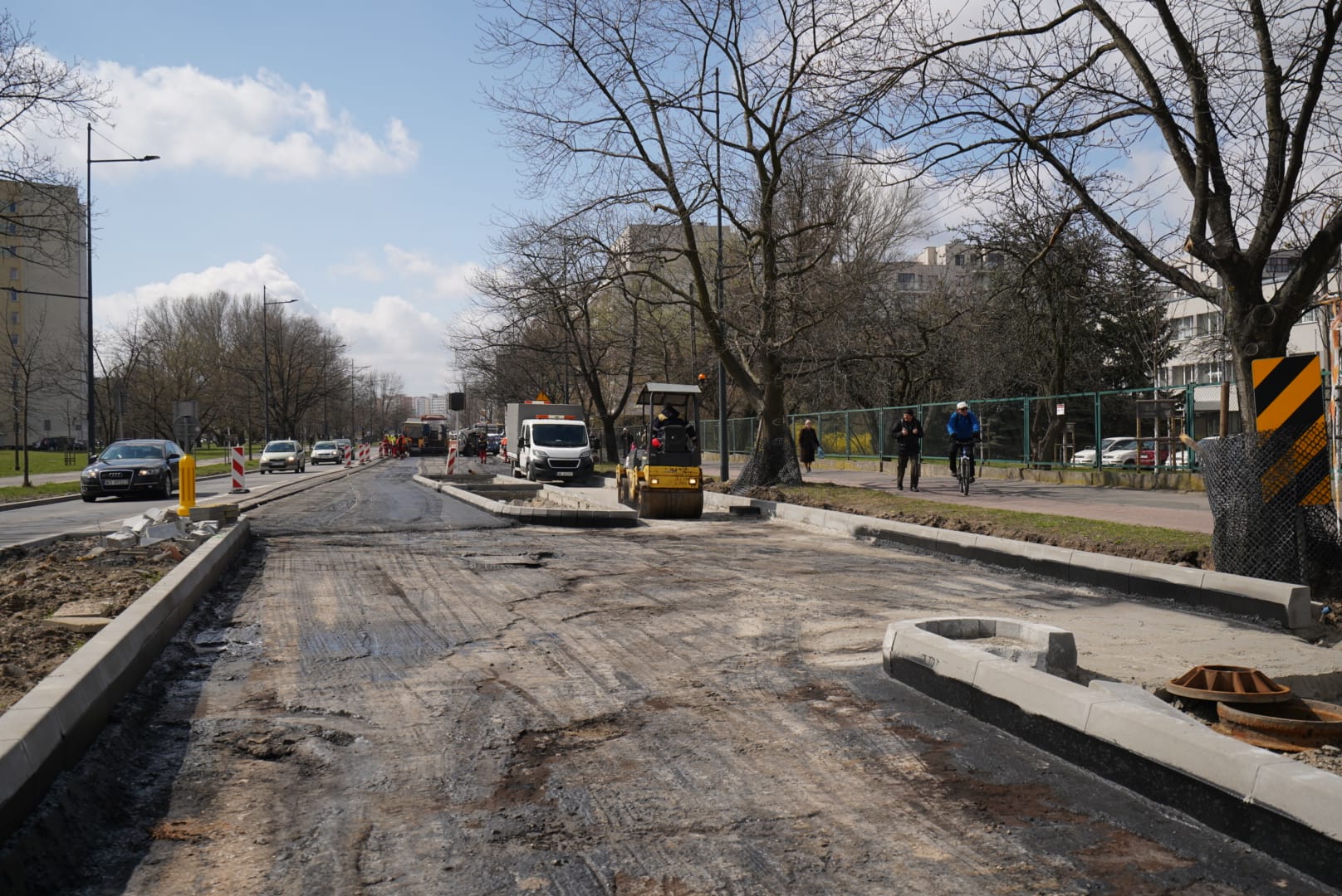 Trwają prace drogowe, robotnicy i maszyny naprawiają asfalt