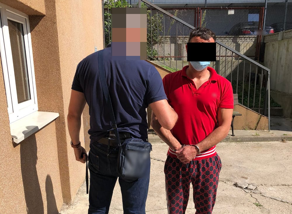 Policjant aresztujący mężczyznę w kajdankach