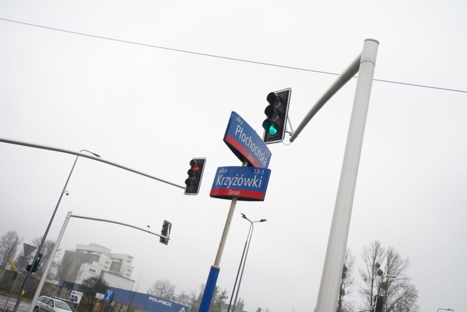 Znaki drogowe dla ulic Płochocińskiej i Krzyżówki w Żeraniu w Polsce, ze światłami w kolorze czerwonym i zielonym.