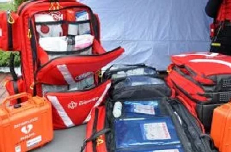 Różne czerwone plecaki i walizki medyczne wypełnione sprzętem pierwszej pomocy.
