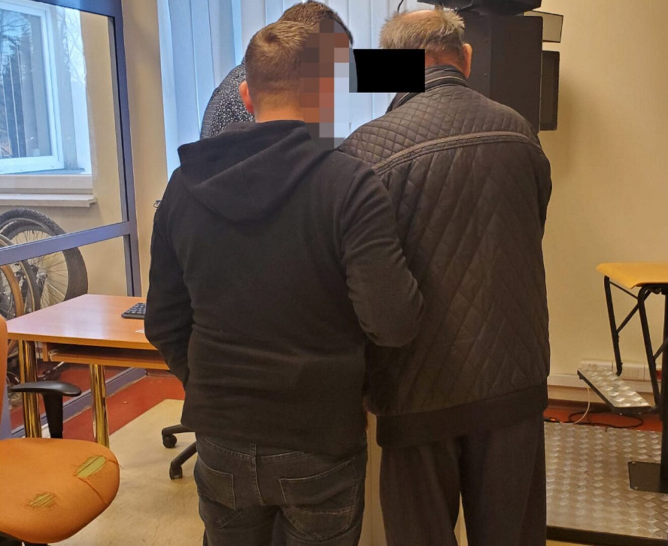 Dwóch mężczyzn przy komputerze, twarz jednego z nich została zamazana w celu zachowania prywatności.