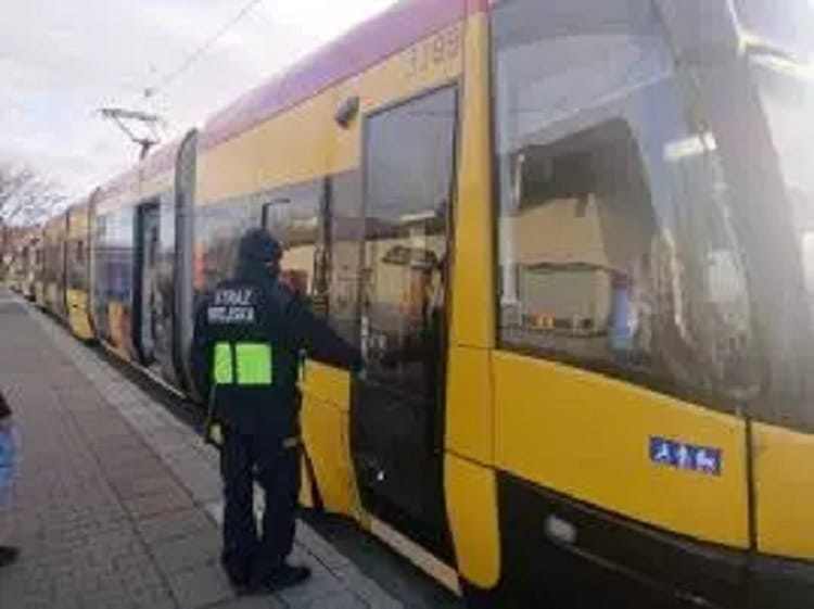 Policjant przeprowadzający inspekcję żółtego tramwaju.