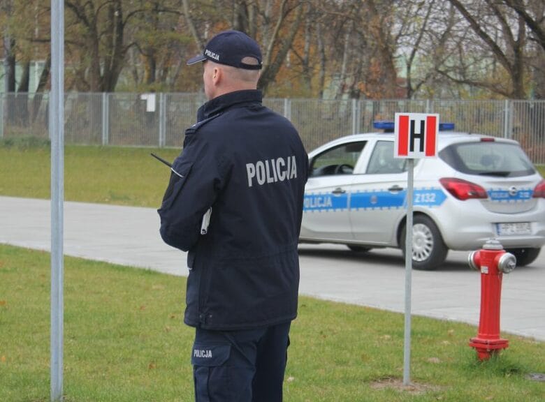 Polski policjant w mundurze przy radiowozie