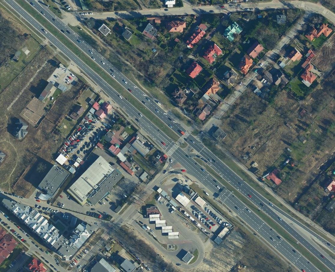 Widok z lotu ptaka na skrzyżowanie autostrad w pobliżu osiedla mieszkaniowego i salonu samochodowego.