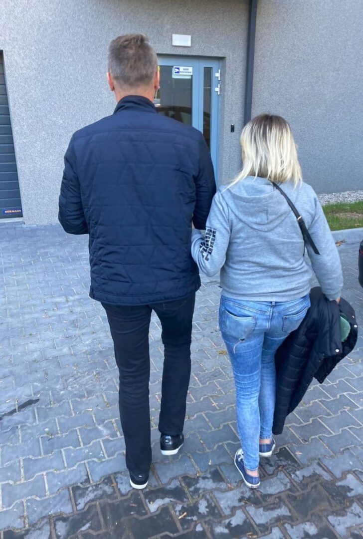 Mężczyzna i kobieta odchodzą od wejścia do budynku.