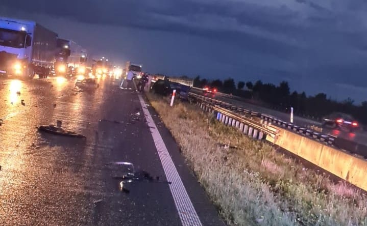 Nocny wypadek na autostradzie z udziałem wielu pojazdów, na drodze leżą rozrzucone szczątki.