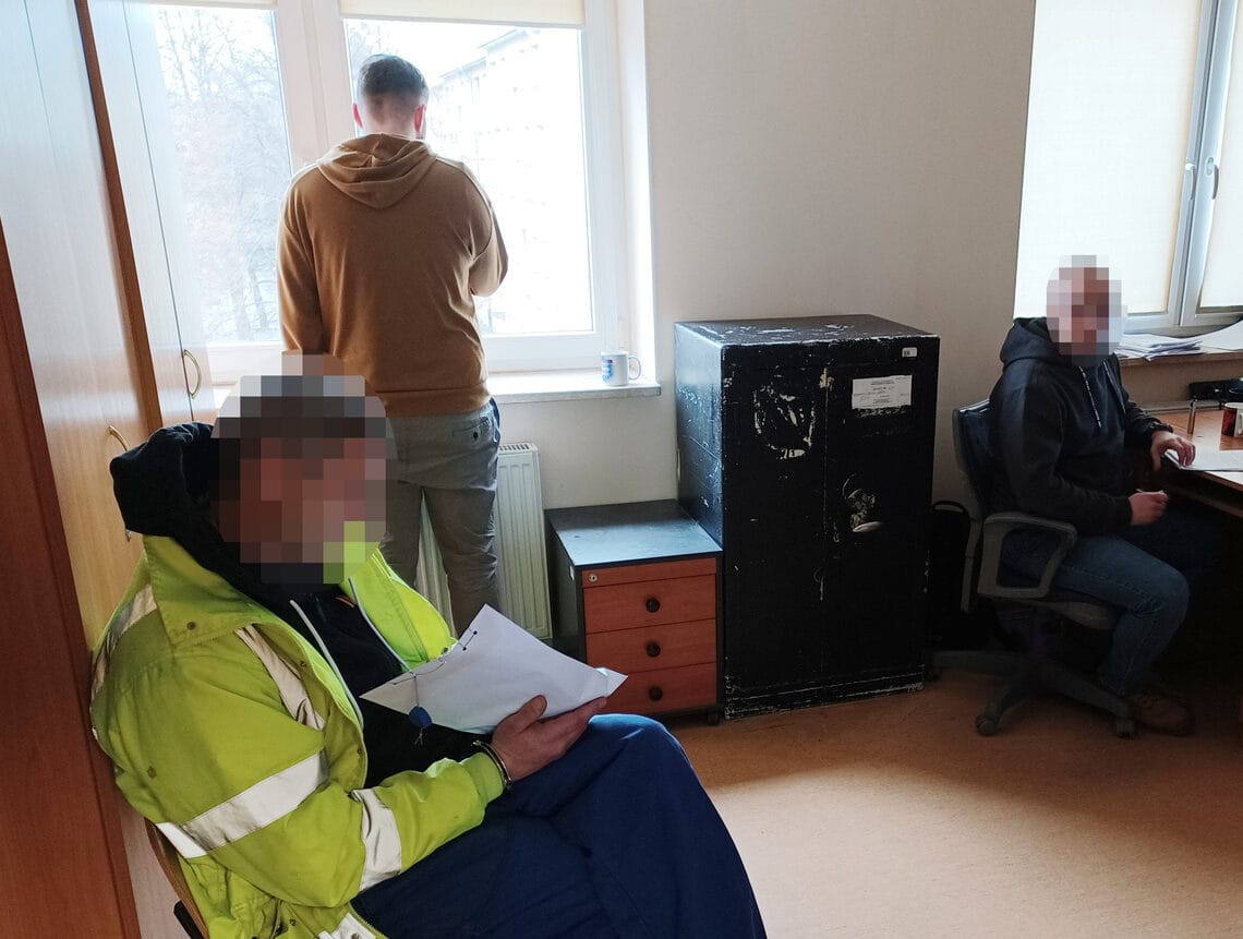 Trzech mężczyzn w pokoju, jeden przegląda dokumenty. Ochrona biura.