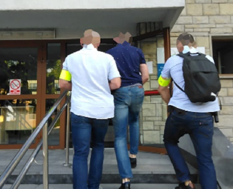 Trzech mężczyzn ubranych w dżinsy i koszule wchodzi po schodach na zewnątrz budynku.