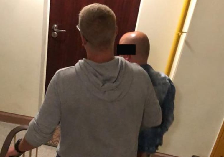 Dwóch mężczyzn na schodach, jeden w szarej bluzie z kapturem.