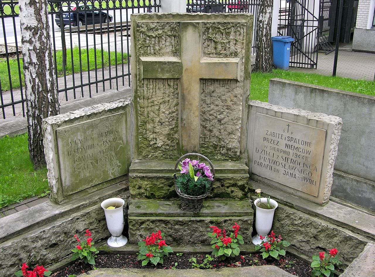 Kamienny krzyż pamiątkowy z napisem: „Zabite i spalone przez Niemcow w sierpniu 1944 r.” Ofiary II wojny światowej.