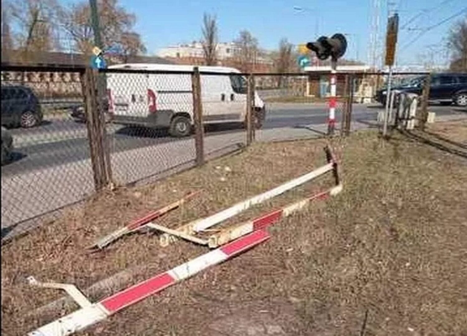 Zniszczona brama przejazdu kolejowego na ziemi w pobliżu drogi.