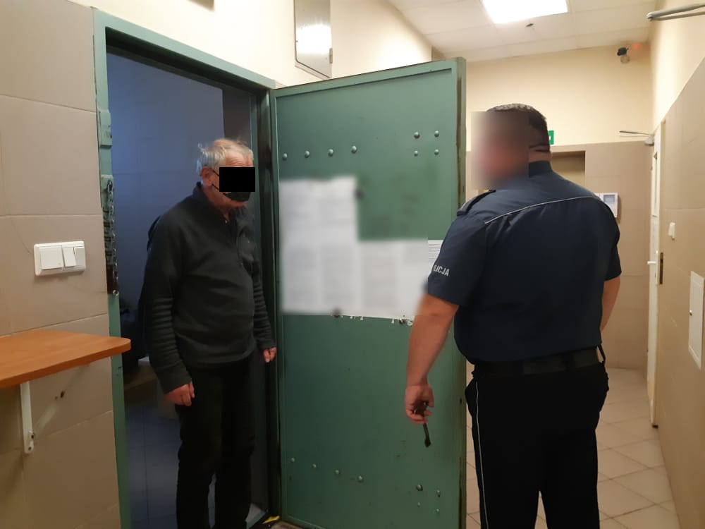 Policjant i zatrzymany mężczyzna w celi więziennej.