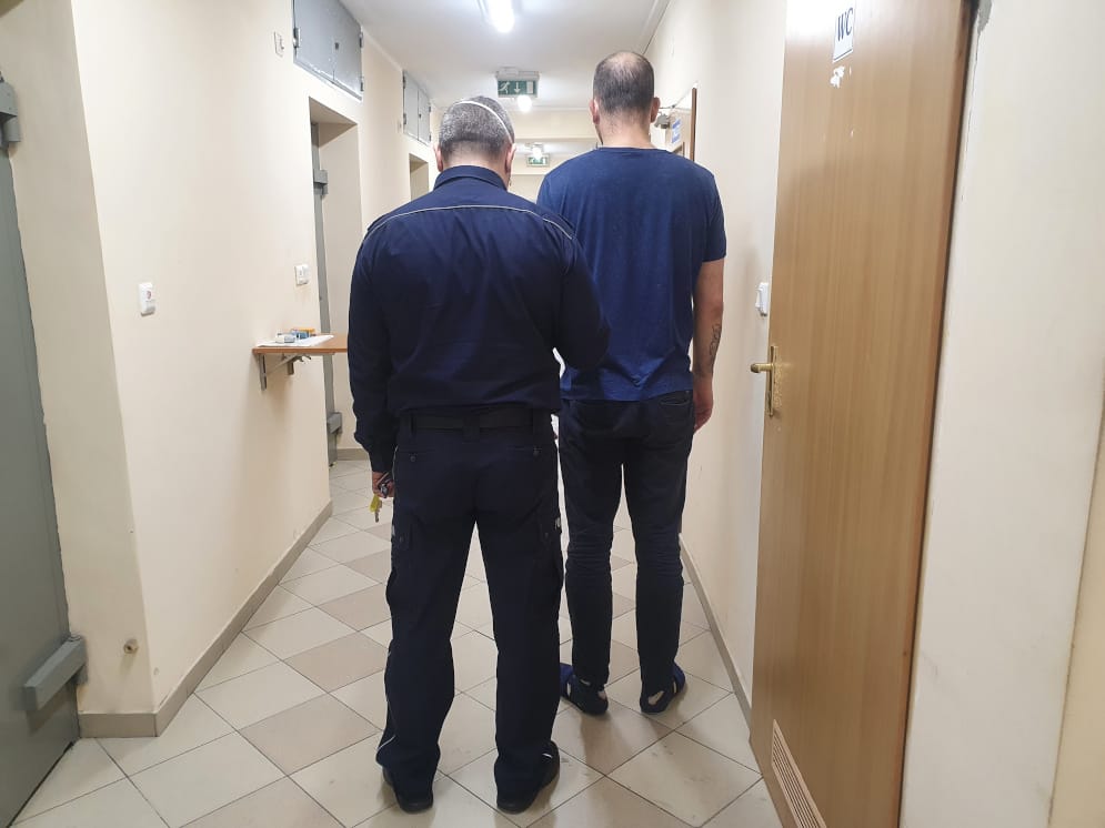 Policjant eskortujący więźnia korytarzem.